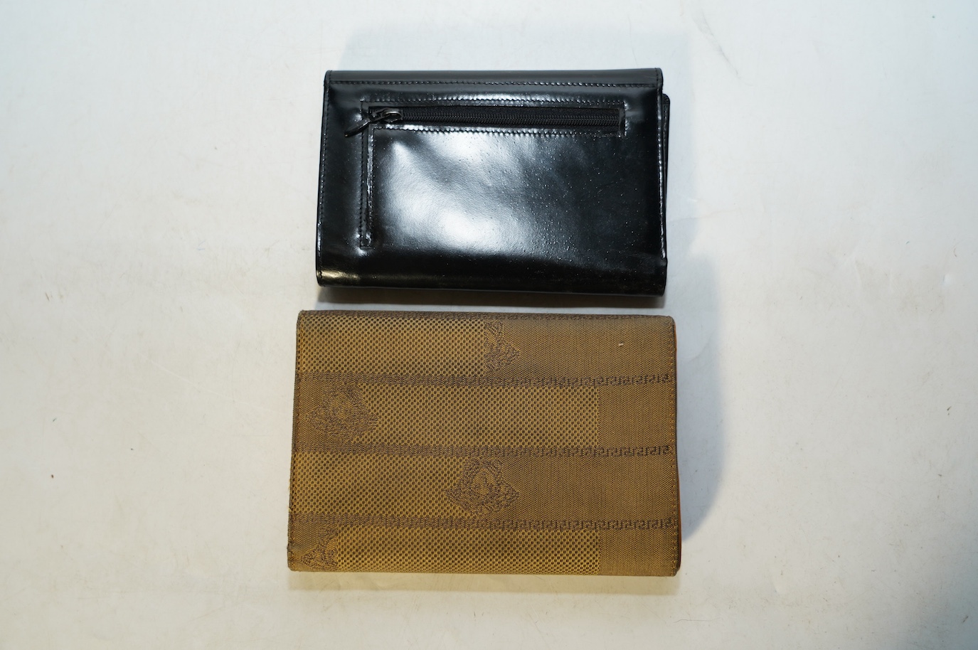 A Gucci black leather wallet and a Versace canvas wallet